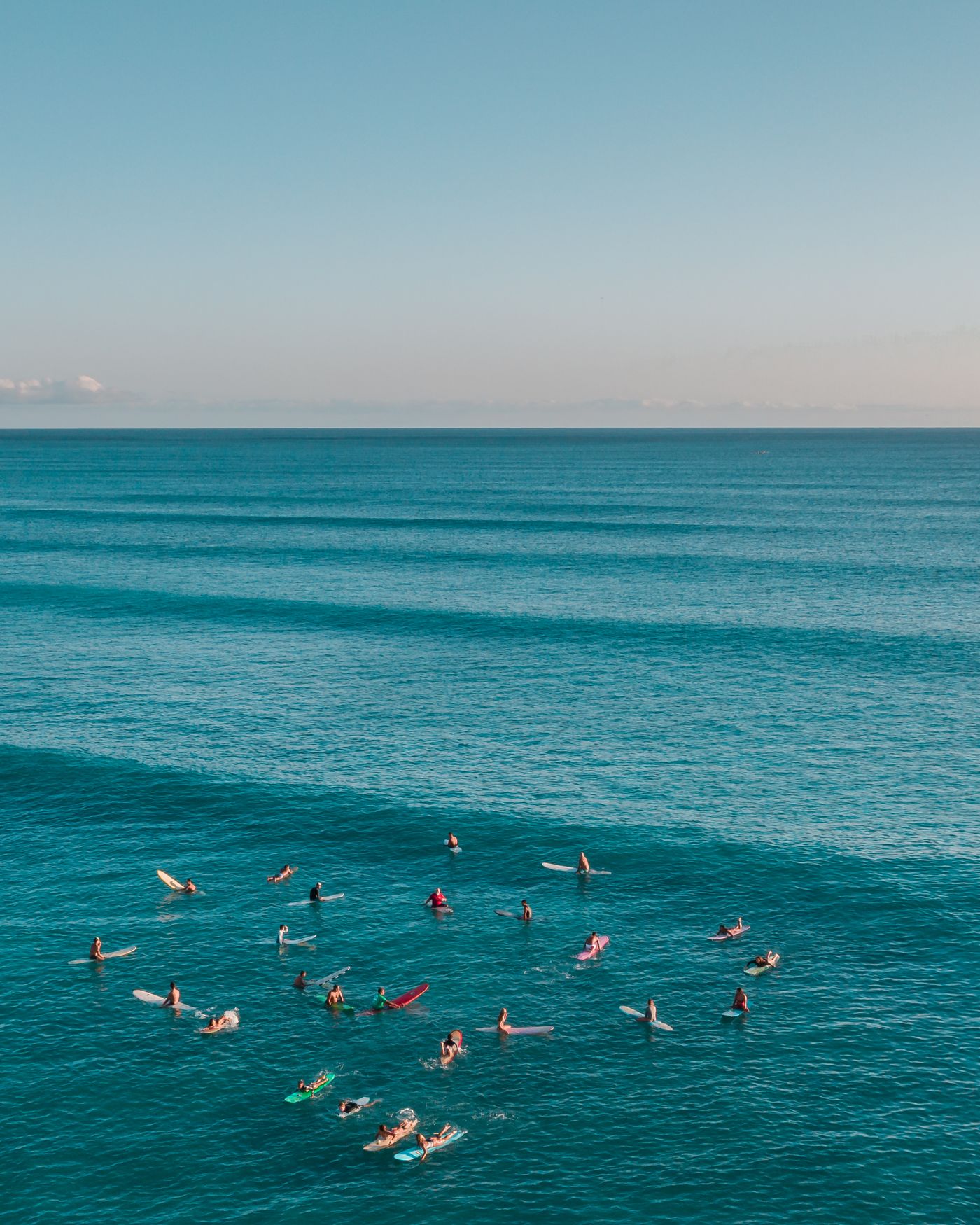 Surfers wait together on their boards beyond the breaking waves.