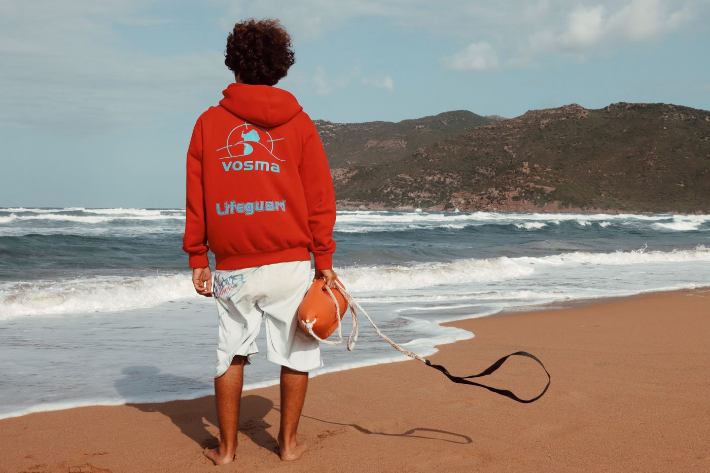 A lifeguard looks across the water from a sandy shoreline.