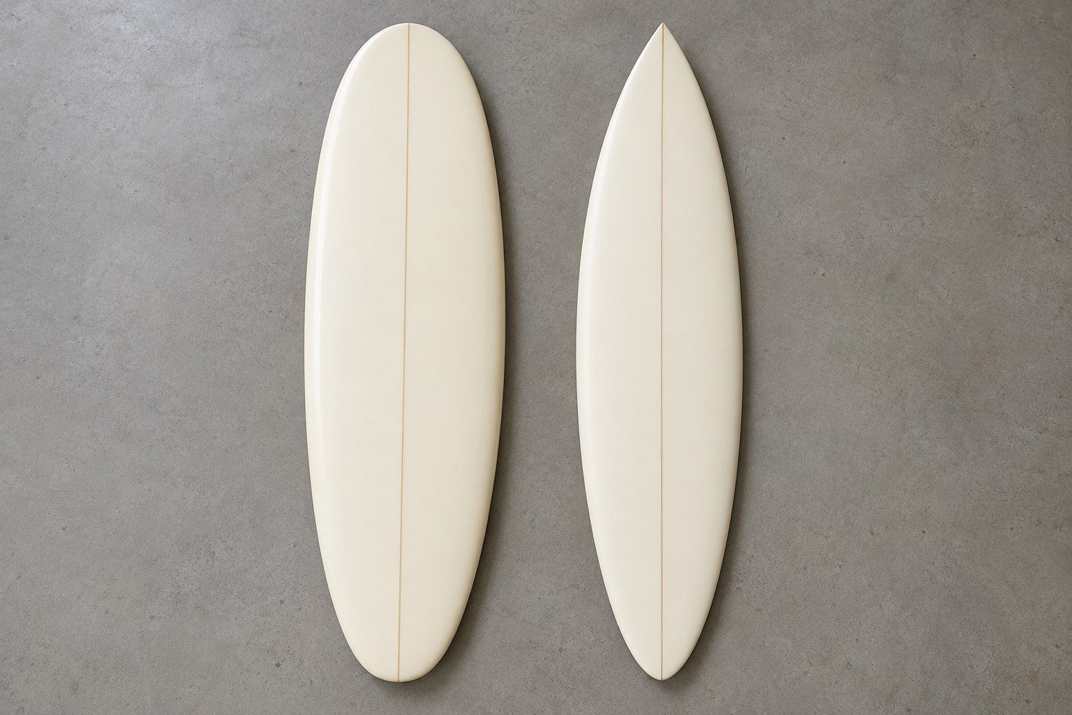 A wide rounded surfboard and a narrower pointed board lie deck-side up for an outline comparison.